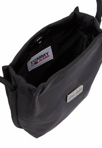 Borsa in nylon nera con cordino e manico intrecciato, accentata da un logo argentato e una superficie liscia e texture. L'interno presenta una fodera nera.