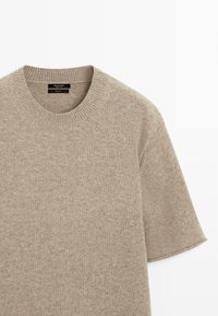 Maglione beige lavorato a maglia con scollo rotondo e maniche corte. Presenta una scollatura a coste e una texture morbida, progettato per un uso casual.