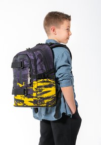 Zaino con un design astratto viola e giallo. Realizzato in tessuto resistente, presenta spallacci regolabili e diversi scomparti.