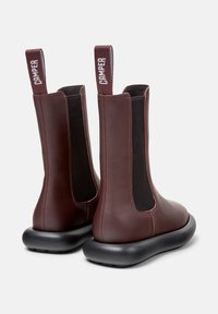 Bordeauxfarbene Leder-Stiefeletten mit schwarzen elastischen seitlichen Einsätzen und Zuglaschen, ausgestattet mit einer dicken schwarzen Gummisohle für Komfort.