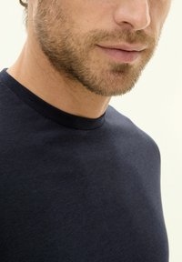 Navy blue T-shirt with a round neckline, short sleeves, and a soft texture, featuring a close-up view of the collar and upper chest area.