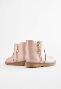 Roségoldene Ankle Boots mit strukturiertem Finish, seitlichen Reißverschlüssen mit herzförmigen Zippern und stabilen braunen Gummisohlen.