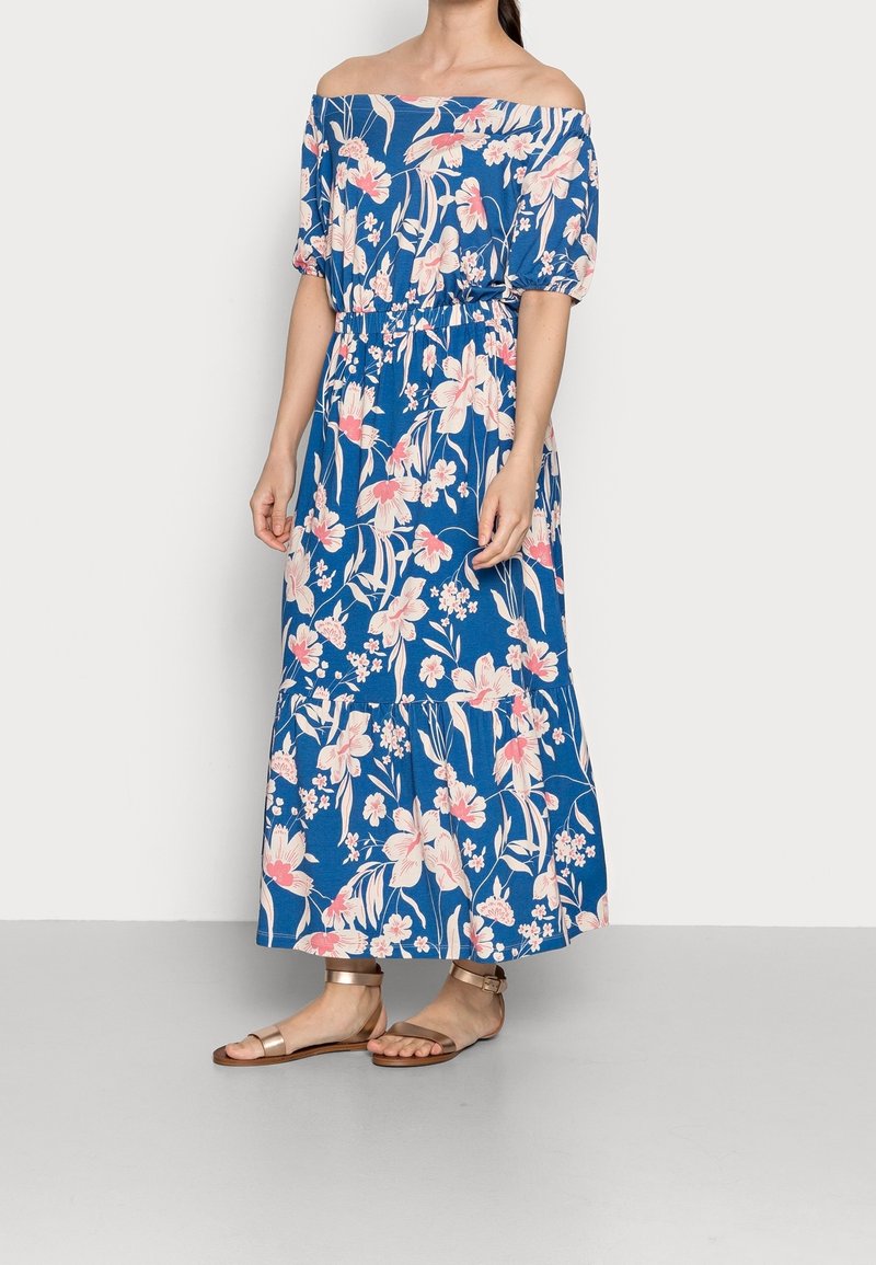Robe maxi bleue à épaules dénudées avec un motif floral en rose et blanc, taille élastique, manches courtes et silhouette fluide.