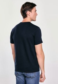Námorně modré tričko s krátkým rukávem, vyrobené z bavlny, s kulatým výstřihem. Jednoduchý design s hladkou texturou a běžným střihem.