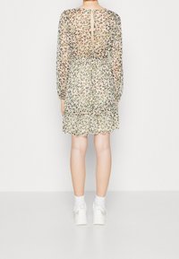 Květinové, průsvitné šaty v pastelových barvách, s dlouhými rukávy, s volánovým lemem ve vrstvách a detailem otvoru na zádech. Stylizované s bílými teniskami.