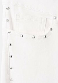 Tissu en denim blanc avec une petite poche et des rivets argentés sur le côté, mettant en valeur une finition texturée et des accents métalliques.