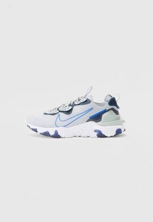 Deportivas Nike en malla gris y azul, con una suela texturizada, detalles en azul y un collar acolchado para mayor comodidad.