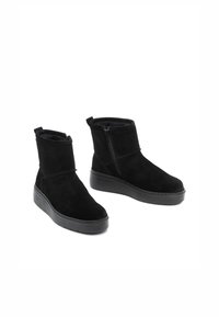 Czarne zamszowe botki za kostkę z okrągłym noskiem, bocznym zamkiem błyskawicznym i grubą czarną gumową podeszwą, z miękką podszewką dla komfortu.