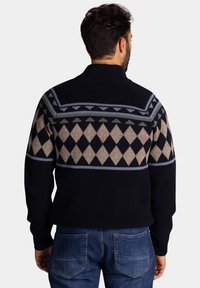 Marineblauwe gebreide trui met een gestructureerd diamanten patroon in beige en grijs, voorzien van een hoge kraag en geribde manchetten en onderrand.