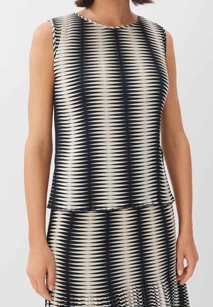 Bezrękawnik w kolorze kremowym i granatowym, z prążkowaną fakturą i wzorem w zygzak. Dół jest lekko rozkloszowany, uzupełniając warstwowy fason.