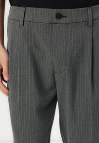 Gray pinstriped trousers with a flat front, single button closure, belt loops, and side pockets, made from textured woven fabric.