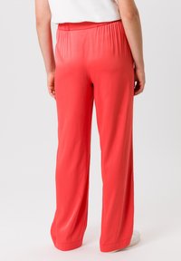 Koraalkleurige broek met brede pijpen en een elastische tailleband, gemaakt van lichtgewicht, soepel materiaal. Kenmerkt zich door een relaxte pasvorm en gedetailleerde stiksels aan de zomen.
