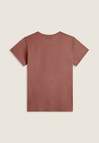 Camiseta de manga corta y cuello redondo en color rosa polvo, fabricada en algodón, con un sutil detalle del logo de Disney en la parte trasera. Textura suave.