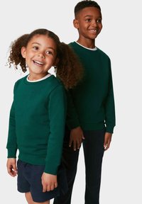 Gröna sweatshirts med ribbad mudd och halsringning, som bärs av två barn, ihopparat med marinblå shorts och byxor, med mjuka texturer.