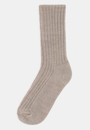 Calzino a coste color marrone chiaro con una texture morbida, lunghezza a metà polpaccio e punta rinforzata. Design semplice senza motivi o accenti aggiuntivi.
