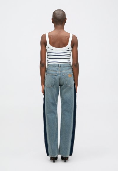 Triibuline, ilma varrukateta valge tank top, millele on sobitatud kõrge vöökoht sinised teksased, millel on tumedamad külgtriibud ja sirge jalgade lõige.