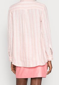Camicia a righe rosa chiaro con maniche lunghe, caratterizzata da una vestibilità rilassata e un tessuto morbido. La vista posteriore mostra un orlo arrotondato.