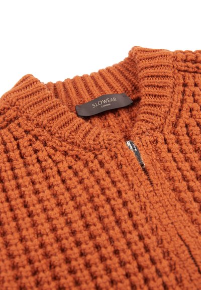 Teksturowany pomarańczowy sweter z żeberkowym kołnierzem i zamkiem błyskawicznym. Tkanina ma wzór tkany. Metka głosi "SLOWEAR ZANONI."