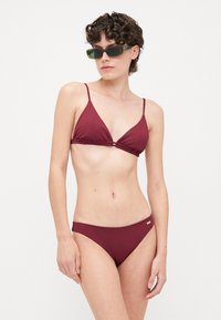 Burgunderfarget ribbestrikket bikini med trekantet topp og matchende bunn. Har tynne justerbare stropper og subtil merking på midjebåndet.