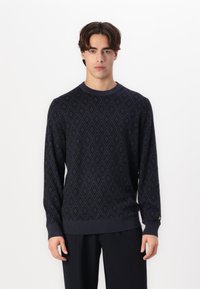 Navyblauwe gebreide trui met een ruitpatroon, geribde boorden en zoom, en een klein accentdetail op de mouw.