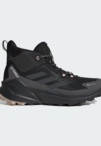 Scarpa da trekking nera alta con suola testurizzata, allacciatura frontale e marchi Gore-Tex e Terrex sui pannelli laterali.