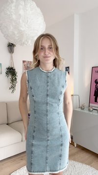 Vestido de ganga azul claro ajustado com um decote alto, design sem mangas, bordas desfiadas e detalhes de costura que correm verticalmente pela frente.