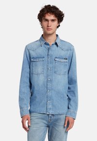 Lichtblauwe denim shirt met lange mouwen, borstzakken, puntige kraag en zilveren knopen aan de voorkant. Soepele textuur en klassiek ontwerp.