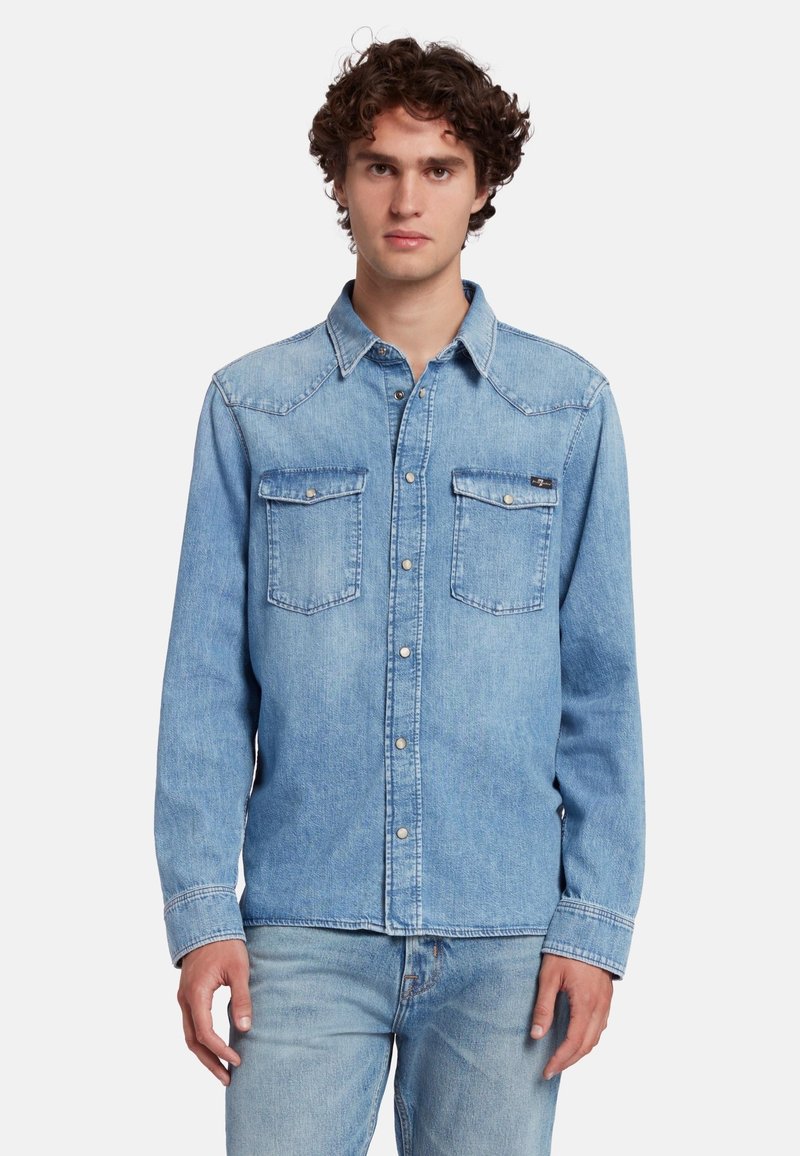 Lichtblauwe denim shirt met lange mouwen, borstzakken, puntige kraag en zilveren knopen aan de voorkant. Soepele textuur en klassiek ontwerp.