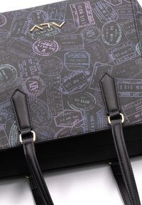 Sac à main noir avec un design à motifs de timbres de voyage multicolores. Texture lisse avec quincaillerie dorée et longues sangles pour l'épaule.