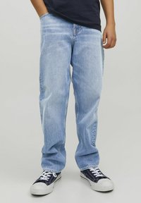 Jean en denim bleu clair avec une coupe ample, jambe droite et décoloration subtile. Assortis avec des baskets en toile noires dotées d'accents blancs.