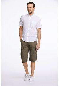 Weißes Kurzarm-Hemd mit Knöpfen und Tasche, kombiniert mit olivgrünen Cargo-Shorts. Modell trägt weiße Sneakers.