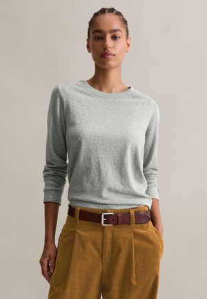 Grey long-sleeve shirt with a crew neckline, paired with mustard-colored pleated pants and a brown leather belt. Smooth fabric texture.