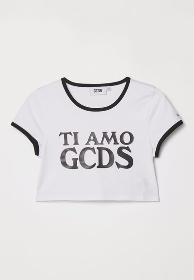 T-shirt cropped branca com detalhes pretos. A parte da frente exibe o texto "TI AMO GCDS" em letras pretas em negrito. Feita de material de algodão macio.