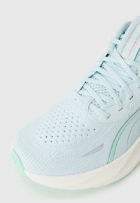Baskets de course Puma bleu clair avec tige en maille, détails en mesh et semelle blanche, vue d'un angle avant.
