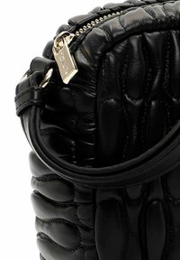 Schwarze gesteppte Lederhandtasche mit gepolstertem Muster, goldfarbenem Reißverschluss und abgerundetem Griffdetail.