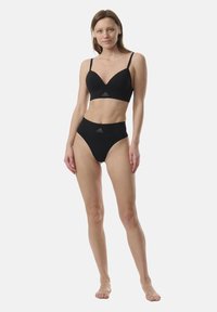 Svart sport-bh med justerbara band, smidig tyg och logotypdetalj. Höga svarta underkläder, sömlös design och åtsittande passform.