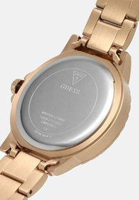 Roségoldener Edelstahluhren mit einem runden silbernen Gehäuse, wasserdichtem Hinweis und Markenprägung auf der Unterseite. Metallarmband.