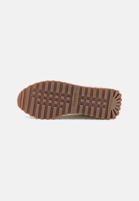 Brown rubber shoe sole with a pronounced tread pattern and a circular textured accent at the heel. Marked with “Blauer USA.”