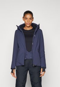 Navy insulated jacket with a high collar, zip closure, and two side pockets. Features thumb holes in sleeves and a sleek, streamlined design.