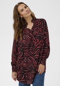 Long-sleeve shirt in red and black with a wavy zebra print, featuring a collared neckline and relaxed fit, made from a lightweight fabric.