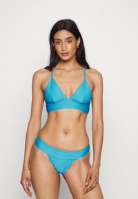 Conjunto de biquíni em dois peças na cor turquesa, com uma textura canelada. O top apresenta um formato em V profundo e alças finas ajustáveis; a parte de baixo tem um corte de cintura baixa.