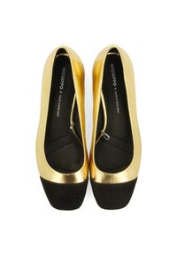 Bailarinas metálicas doradas con una puntera de ante negro. Textura suave con una forma redondeada. Diseño minimalista y estilo de poner y quitar.