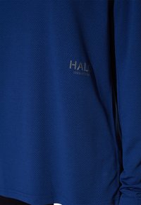 Blauwe mesh longsleeve t-shirt met een textuur, featuring een klein grijs logo aan de voorkant. Ontworpen met een relaxte pasvorm en een ronde halslijn.