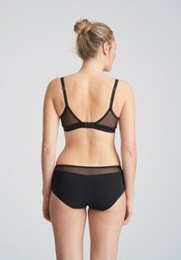 Czarny zestaw bielizny składający się z przezroczystego stanika z regulowanymi ramiączkami oraz dopasowanych majtek. Gładka tekstura o minimalistycznym wzornictwie.