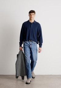 Ναυτικό μακρυμάνικο πόλο μπλουζάκι, ανοιχτό μπλε τζιν, γκρι μπουφάν ριγμένο στο χέρι και μπεζ μποτίνια. Απλή, casual εμφάνιση με μοντέρνα εφαρμογή.