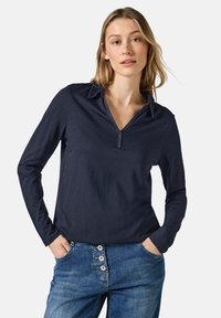 Polo a maniche lunghe navy con scollatura a V e colletto. Presenta una patta con un singolo bottone e una texture di tessuto liscia e leggera.