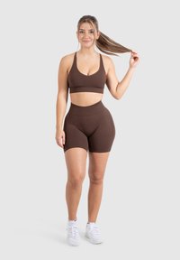 Bruine sportbeha en hoge taille shorts set, gemaakt van rekbaar materiaal. De outfit heeft een eenvoudig ontwerp met brede banden.