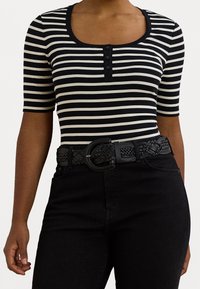 Černé a krémové pruhované krátké rukávy tričko s kulatým výstřihem a třemi knoflíky, doplněné pleteným černým opaskem s kulatou sponou.