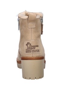 Beige enkellaarsjes met een suède afwerking, imitatiebont voering, zijrits en een houten hak. Heeft een logo patch op de achterkant.