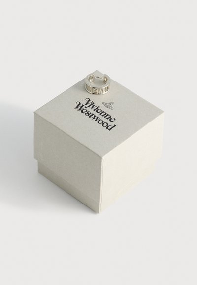 Anillo de plata exhibido sobre una caja cuadrada beige y texturada con "Vivienne Westwood" impreso en negro en la parte superior.